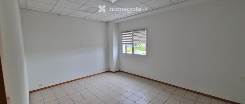 Empty room with white walls, tiled floor, and a single window with blinds.