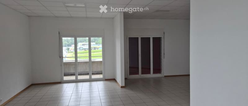 Empty room with white walls, tiled floor, and large glass doors leading to an outdoor area.