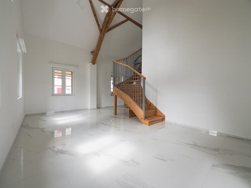 Empty room with white walls, polished marble floor, and a wooden staircase leading upwards.