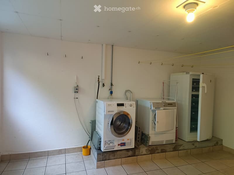Utility room with a washing machine, dryer, and refrigerator. The room has tiled flooring and white walls.
