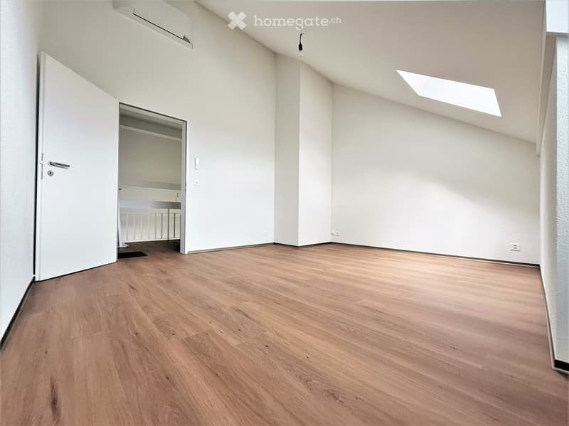 Empty room with wooden flooring, white walls, and a partially open door leading to a closet area.