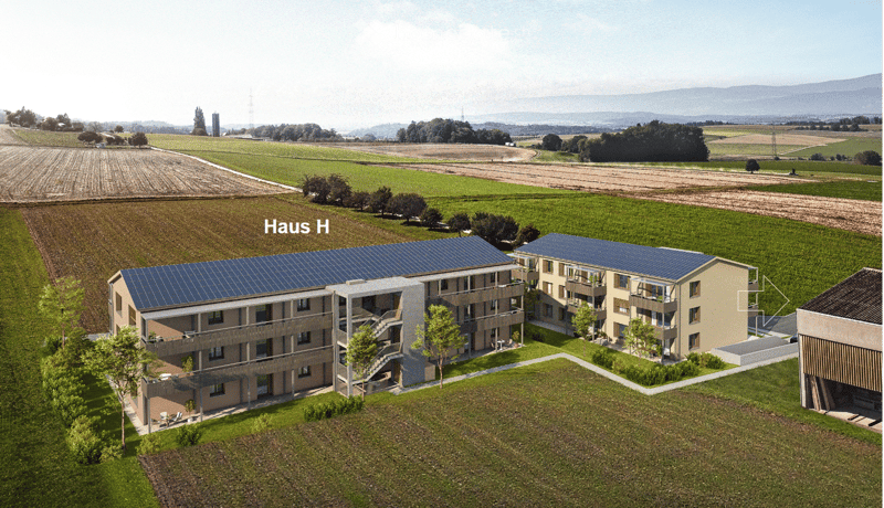 A modern multi-story residential building with solar panels on the roof, surrounded by green fields and trees.
