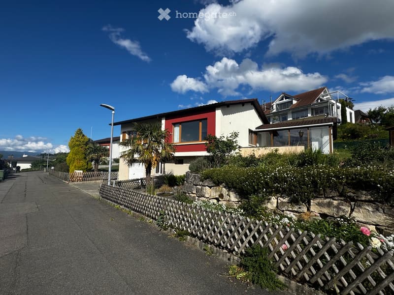 House. Two-story house with red and white exterior, large windows, and a well-maintained garden with a wooden fence.