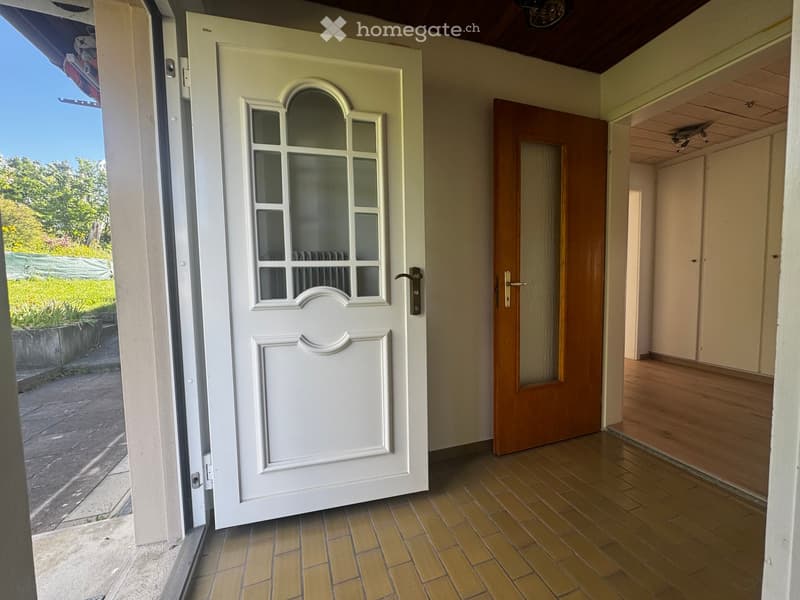 Corridor / Hallway. Entrance hallway with a white front door featuring glass panels, a wooden interior door, and wooden flooring.