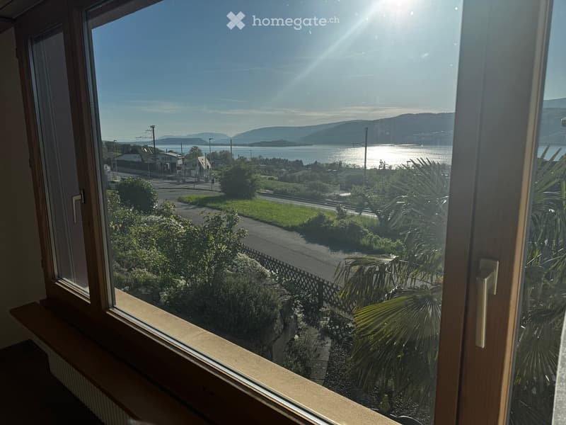 Balcony / Terrace. View from a large window showing a scenic landscape with a body of water, distant hills, and a road leading to nearby houses.