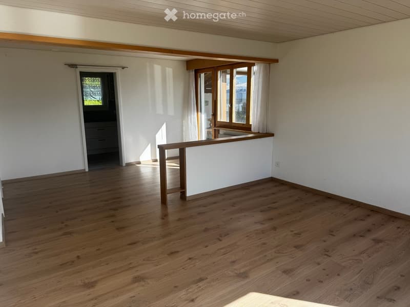 Unfurnished Room. Empty room with wooden flooring, white walls, and large windows with curtains. Features a wooden railing and a doorway leading to another room.