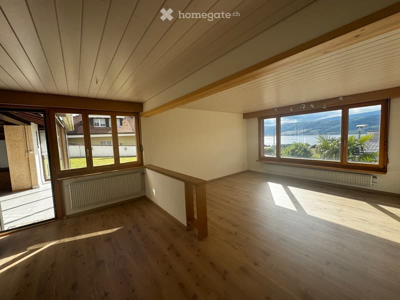 Unfurnished Room. Bright, empty room with wooden flooring, large windows offering scenic views, and built-in wooden beams on the ceiling.