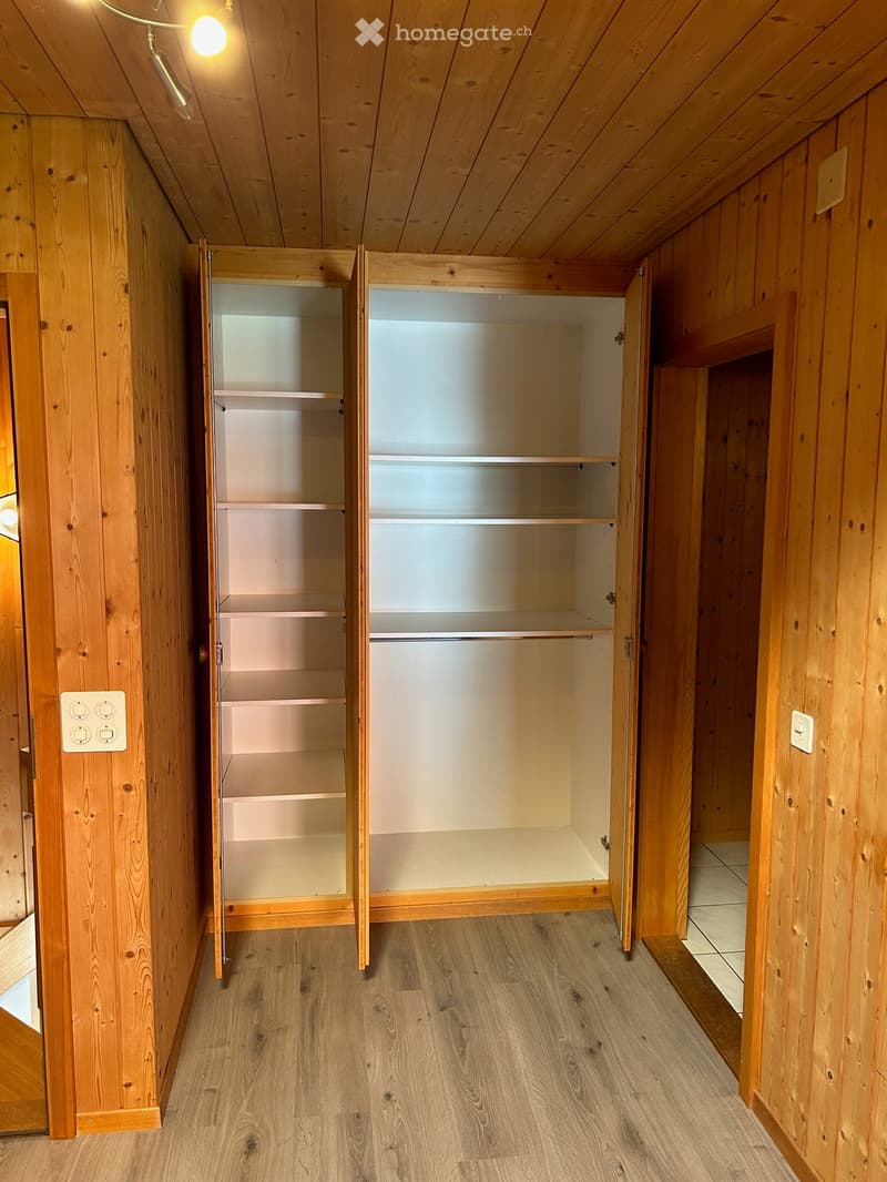 Empty hallway with wooden walls, wooden floor, and built-in wooden shelving units with open compartments.