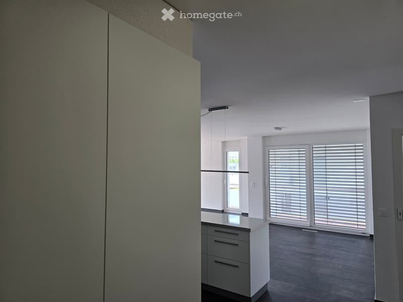 Empty room with modern design, white cabinetry, large windows with blinds, and a dark tiled floor.