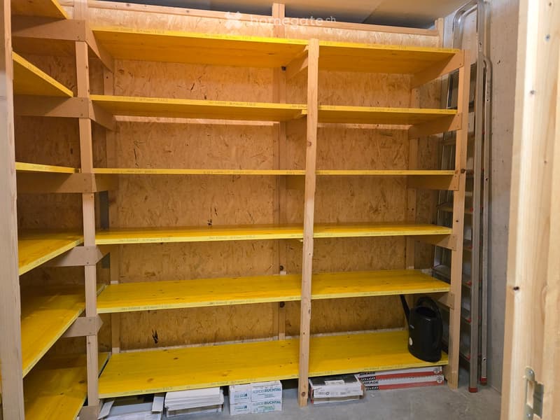 Empty storage room with wooden shelves and yellow measuring tape markings on the walls. No furniture or equipment present.