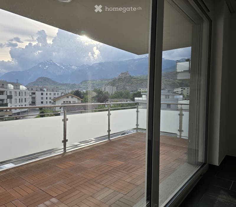 Balcony with wooden decking, metal railing, and scenic mountain view.
