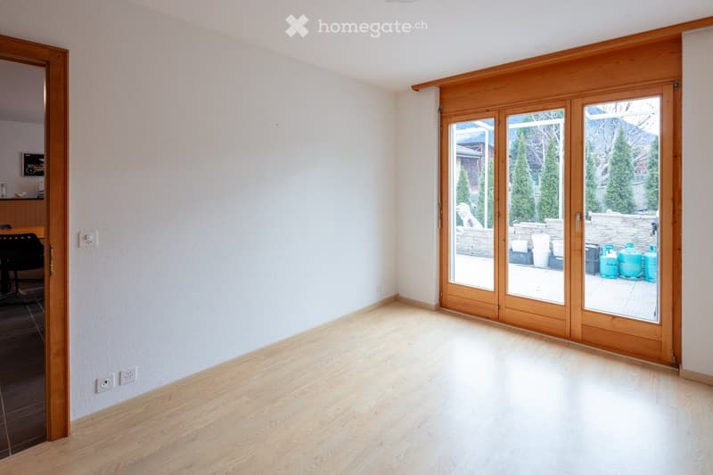 Empty room with light wooden flooring, white walls, and large sliding glass doors leading to an outdoor area.