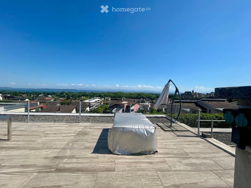 Roof terrace with wooden decking, covered furniture, umbrella, and scenic city view.