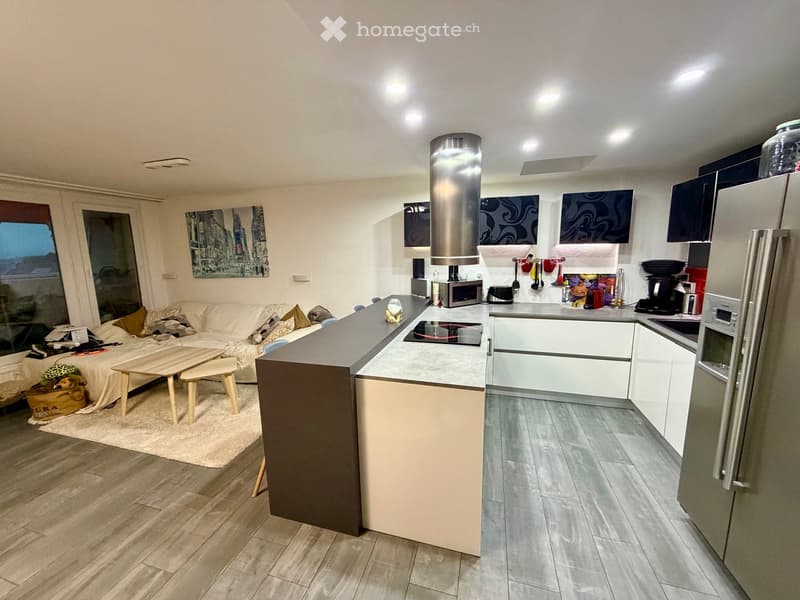 Modern open-plan living and kitchen area with a sofa, coffee table, kitchen island, and various appliances.