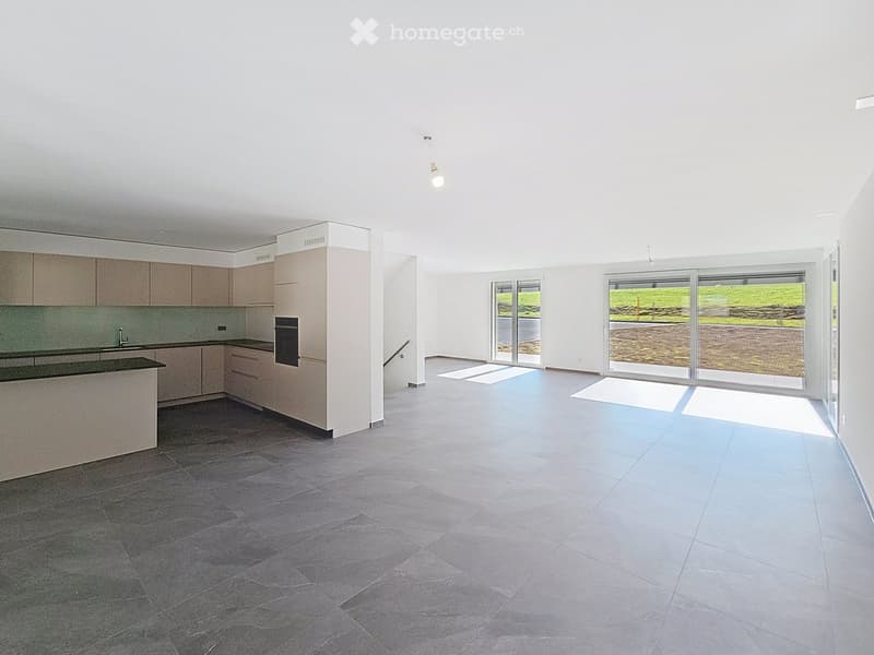 Modern kitchen with light-colored cabinets, dark countertop, and large windows overlooking a green area.