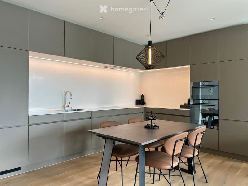 modern kitchen with wooden floor, gray cabinets, white countertops, stainless steel sink, faucet, dining table with chairs, hanging lamp, built-in oven