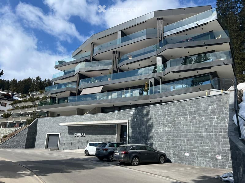 Modern apartment building with multiple balconies, glass railings, and a stone wall facade