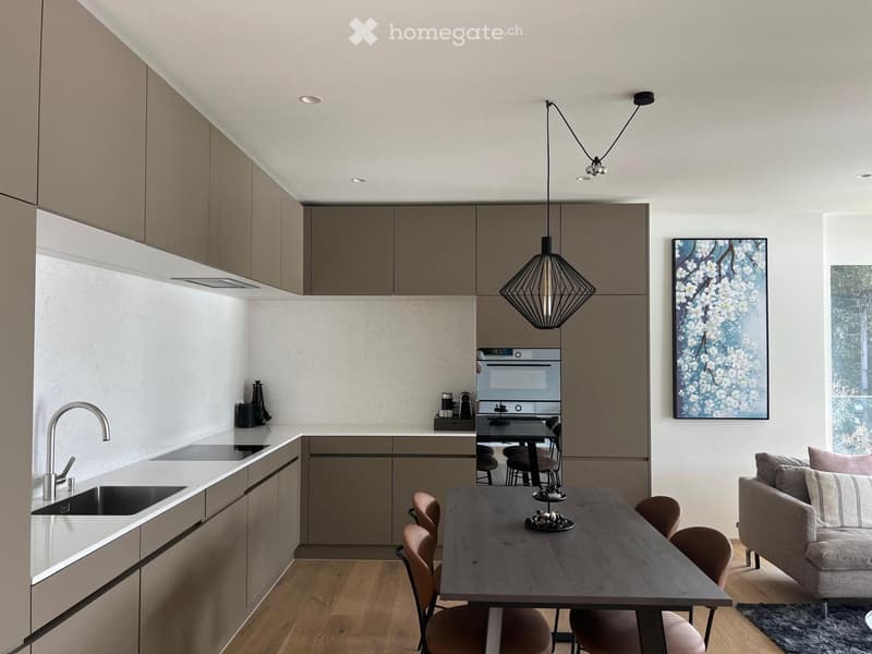 modern kitchen with wooden floor, white countertops, stainless steel appliances, pendant light, dining table, and a couch