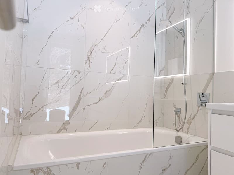 white marble tiles, glass shower enclosure, bathtub, shower head, faucet, white vanity