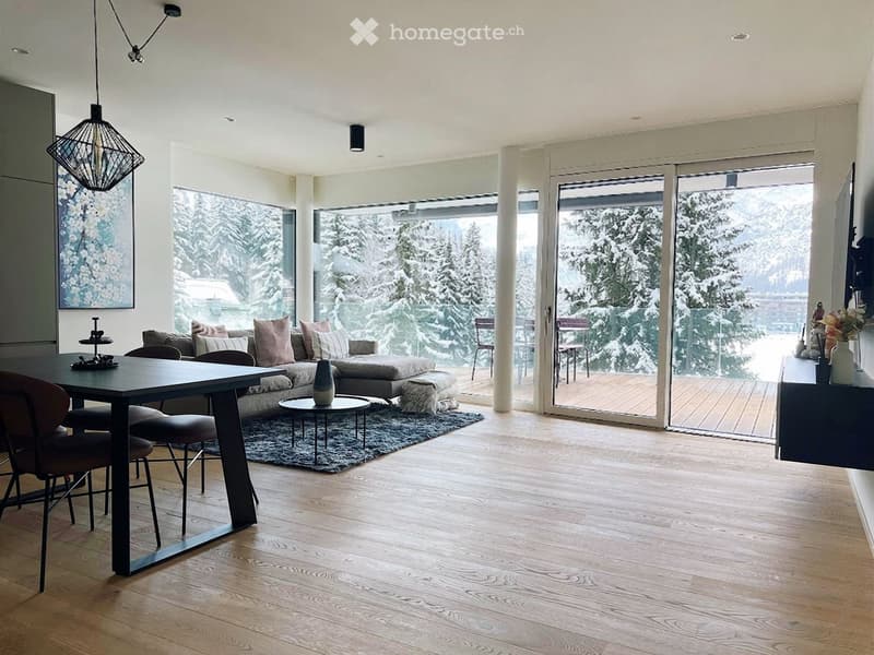 large windows, wooden floor, sofa, coffee table, rug, dining table, chairs, balcony, view of snowy mountains