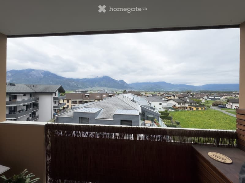 Balcony with a scenic mountain view, featuring a wooden railing and a small table with a circular wooden tray.