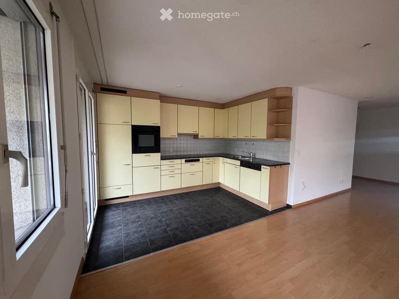 Modern kitchen with light-colored cabinets, black countertops, and a dark tiled backsplash. Features a sink with a faucet, an oven, and a dishwasher.