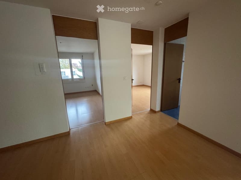 Empty hallway with wooden flooring, white walls, and doors leading to other rooms.