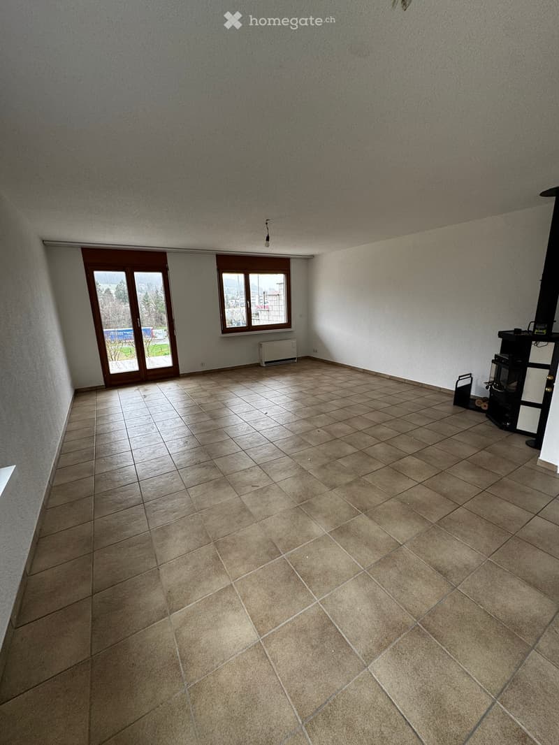 Empty room with tiled floor, large window, and sliding glass door leading outside.
