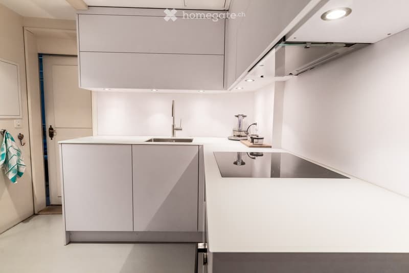 Modern kitchen with white cabinets, a central island, a sink, and a coffee maker on the counter.