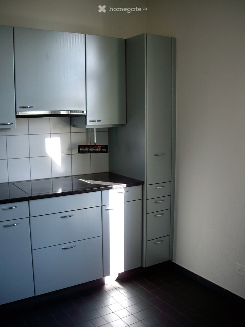 modern kitchen with white cabinets, black countertops, stainless steel appliances, and tiled floor
