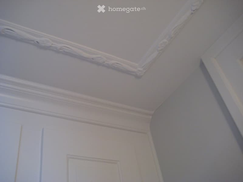 white ceiling with decorative molding, white walls, white door