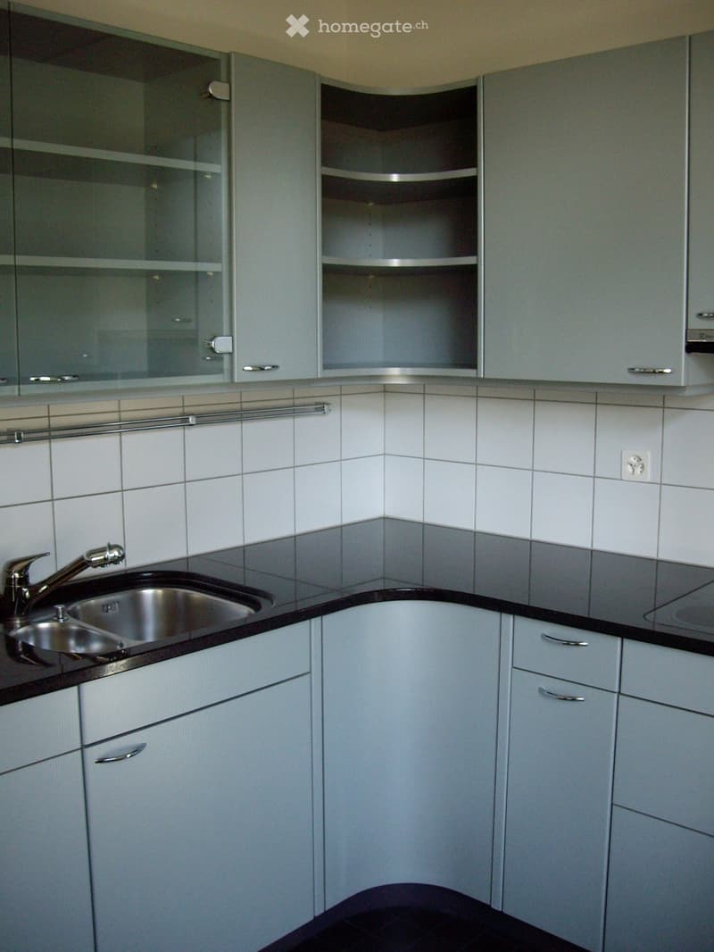modern kitchen with white tiles, gray cabinets, black countertops, stainless steel sink, faucet, power outlet