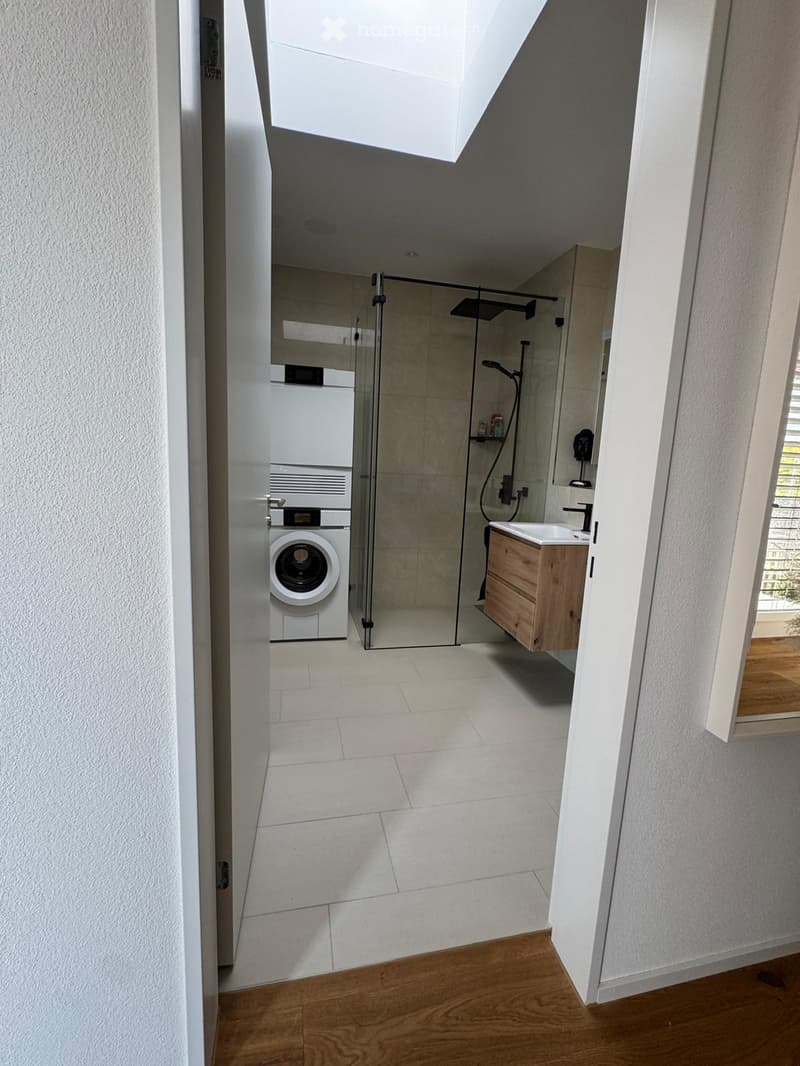 large white tiles, white walls, white door, washing machine, shower area, wooden sink, skylight