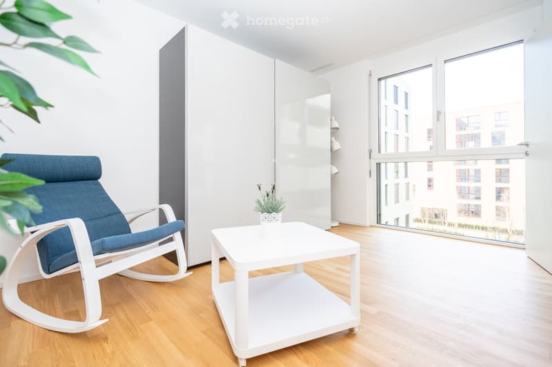 Modern living room with a white rocking chair, white coffee table, potted plant, and large white wardrobe. Large windows offer a view of the city.