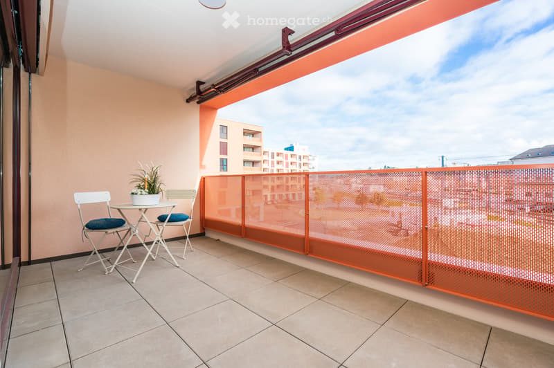 Balcony with tiled floor, white folding chairs, small table with a potted plant, and an orange metal railing.