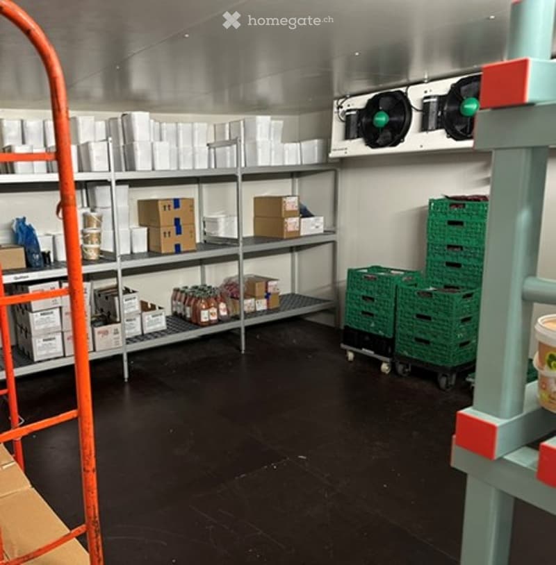 Empty storage room with metal shelving, boxes, and green crates. No furniture or equipment.