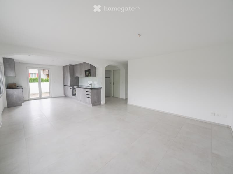 Open-plan space with white tiled flooring, grey cabinetry, and large sliding glass doors leading to an outdoor area.