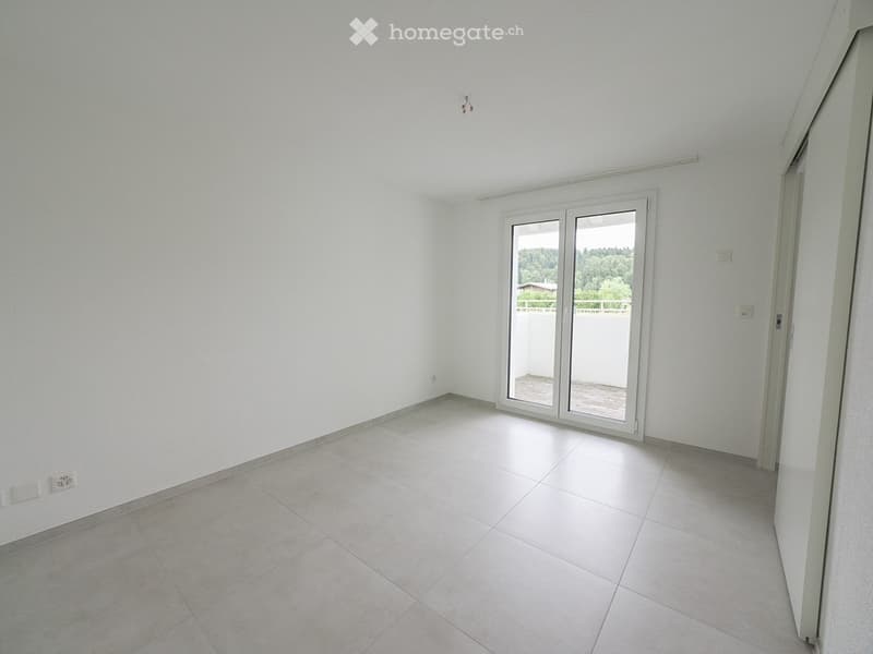 Empty room with white tiled floor and white walls, featuring a large sliding glass door leading to a balcony.