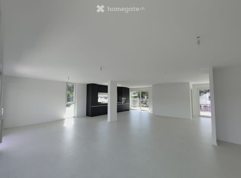 Empty room with white walls, white tiled floor, and a dark kitchen area visible in the background. No furniture or equipment present.