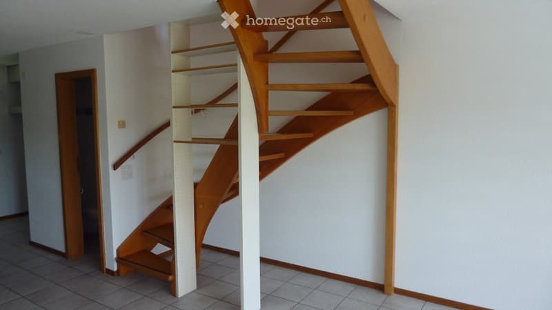 Modern wooden staircase with open design and built-in shelving, leading to an adjacent room.