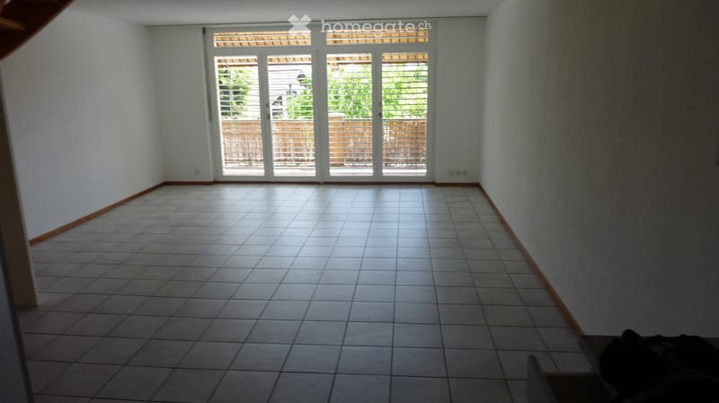 Empty room with tiled floor and large sliding glass doors leading to an outdoor area.