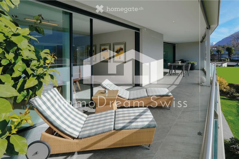 Balcony with sun loungers, a small table, and chairs, overlooking a scenic mountain view.