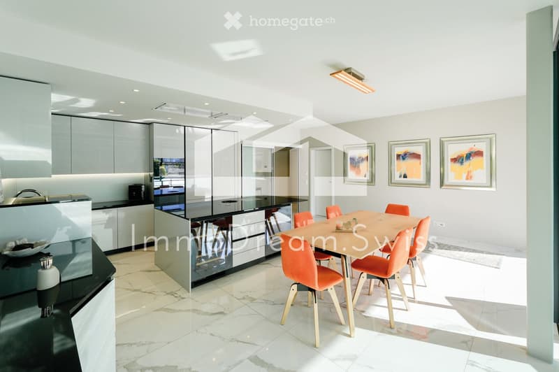 Modern kitchen and dining area with sleek white cabinets, a black countertop, a central island, and a dining table with orange chairs.