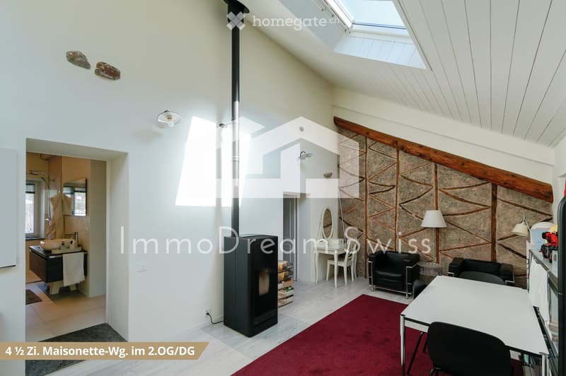 Bright, open living space with a modern fireplace, large skylight, exposed wooden beams, and a mix of contemporary and rustic decor including a sofa, chairs, a table, and a sink area.