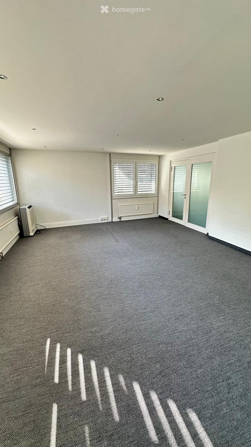 Empty room with grey carpet, white walls, large windows, and a sliding glass door.