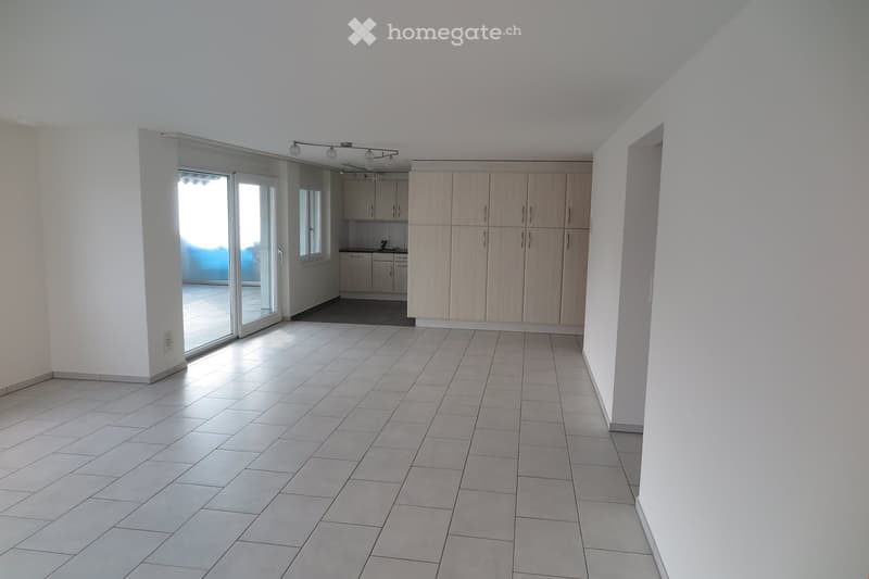Empty room with tiled floor, white walls, and a sliding glass door leading to another room with kitchen cabinets and appliances.