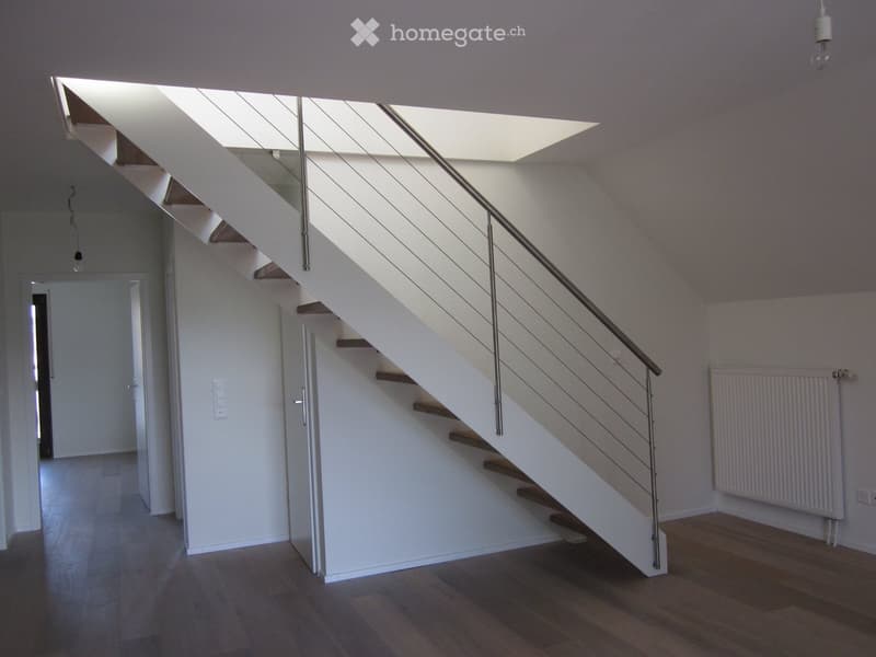 Staircase with wooden steps and metal railing, white walls, white ceiling, light fixture