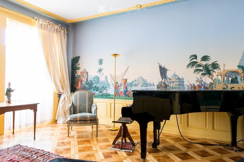 Elegant room with a grand piano, ornate chair, wooden table, large window with curtains, and a detailed mural on the wall.