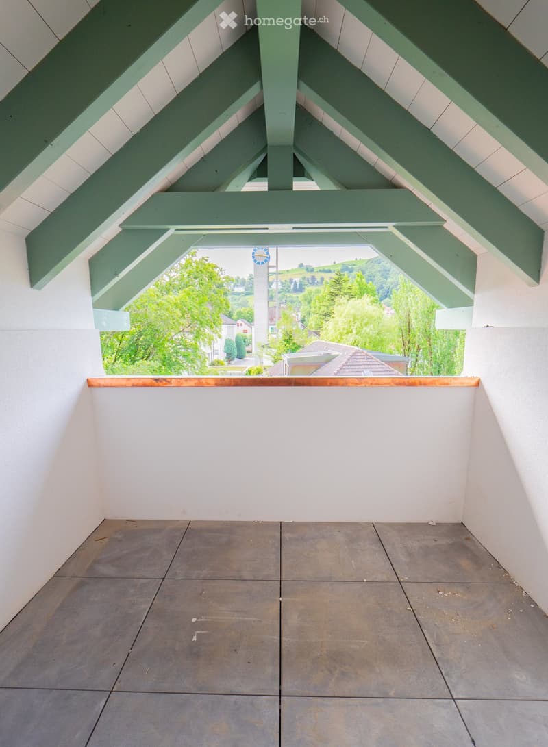 Modern balcony with grey tiled floor, white walls, and a large skylight offering a scenic view of greenery and houses.