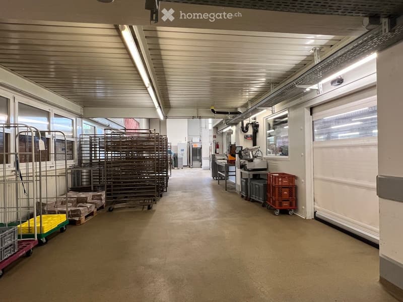 Warehouse with racks, storage boxes, white walls, and ceiling lighting